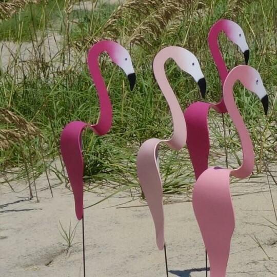 Rosa Flamingo-Deko zwischen Pflanzen im Garten